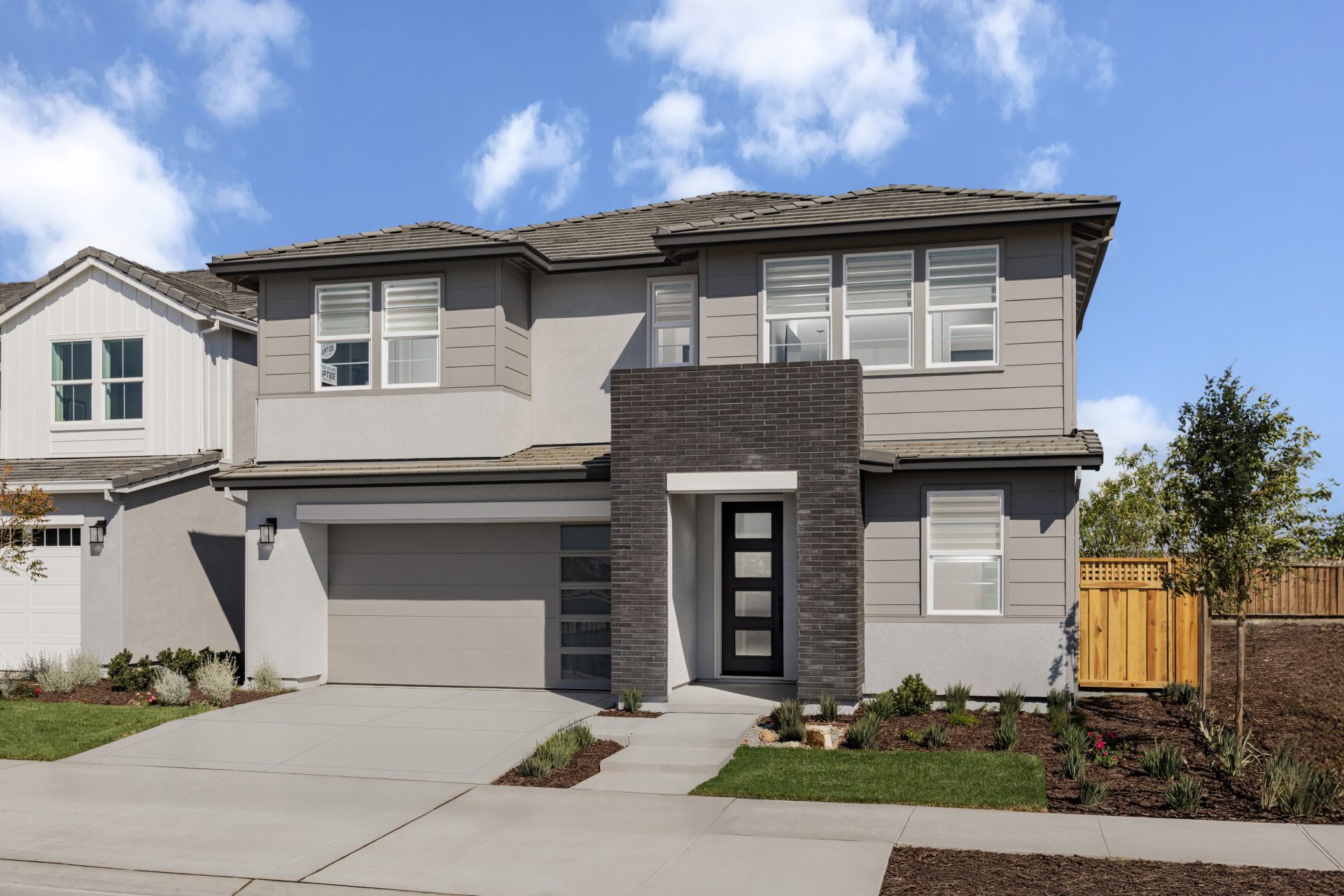 New Kiper Homes single-family home at River Islands with white board-and-batten siding, black trim, and wood accents